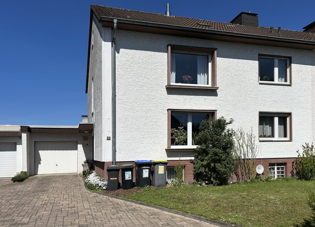 Blick auf ein Zweifamilienhaus in Paderborn Stadtheide mit weißer Fassade und links angebauter Garage.