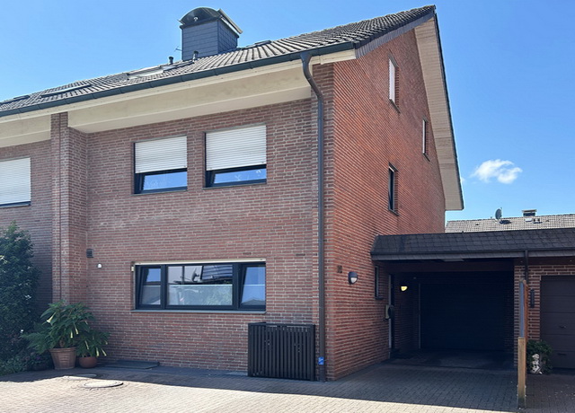 Blick auf eine rot geklinkerte Doppelhaushälfte in Schloß Holte mit angebauter Garage