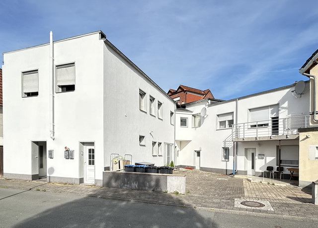 Blick auf ein Mehrfamilienhaus mit weißer Fassade und Flachdach. Die Immobilie befindet sich in der Innenstadt von Lippstadt und ist komplett vermietet.